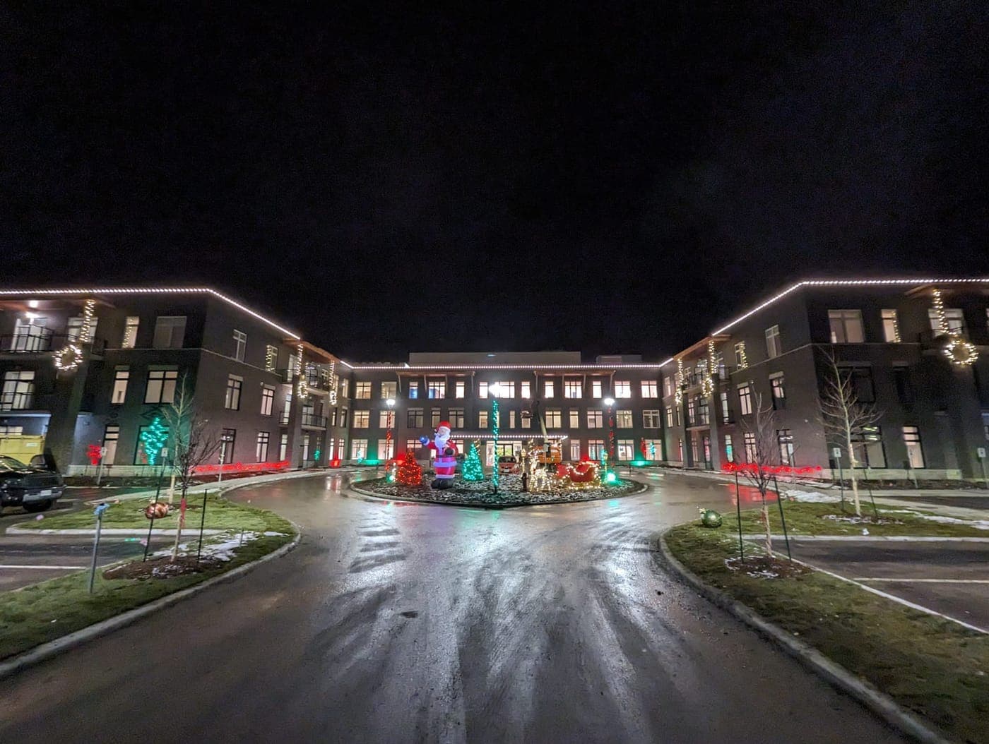 Banks: Large residential complex with warm-white roofline Christmas lights and a holiday courtyard display at the entrance