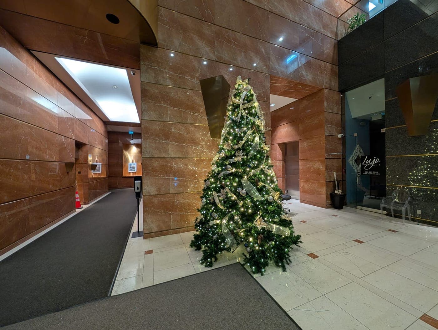 Christmas tree with gold ribbon in a spacious commercial marble lobby with warm-white lighting