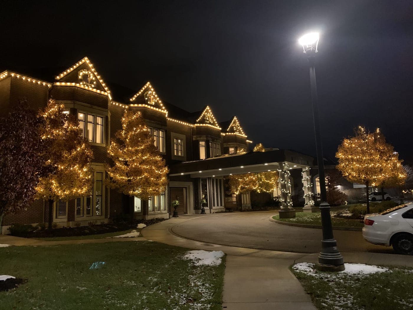 Restaurants: Estate venue with warm-white roofline Christmas lights and a covered entrance wrapped in lights at night