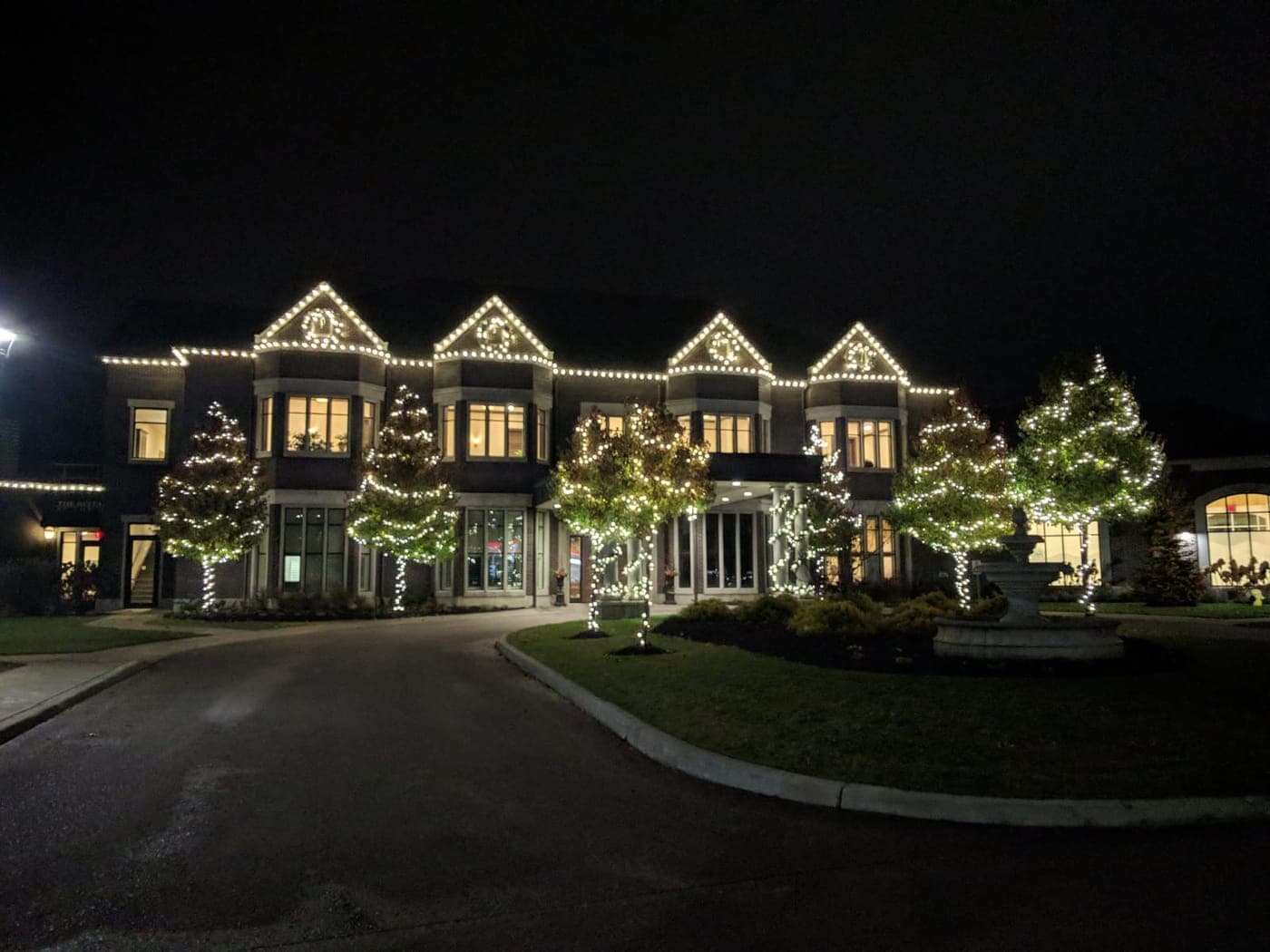 Churches: Grand estate venue lit with warm-white roofline lights and Christmas-wrapped trees at night.