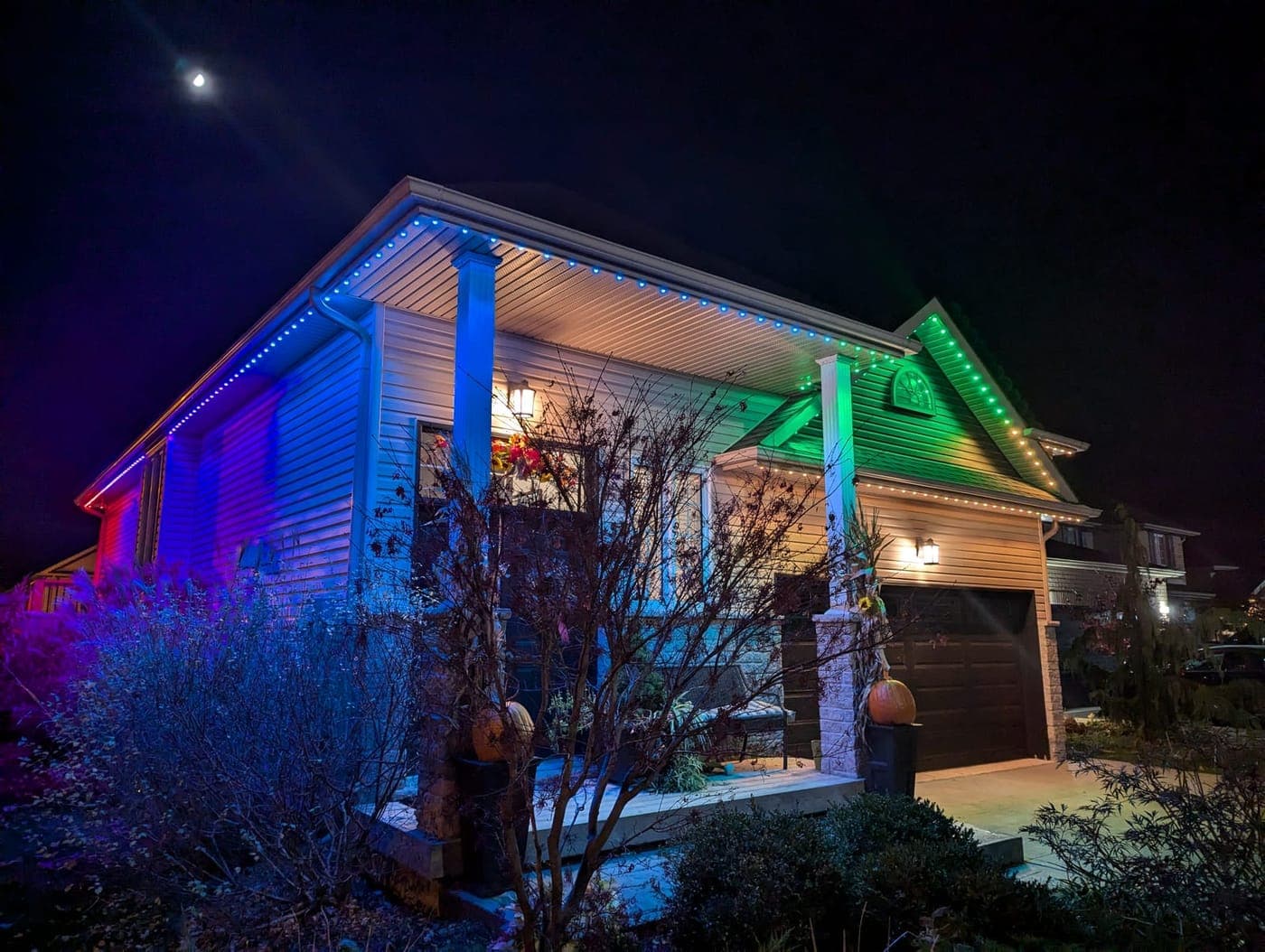 Home lit in blue and green with RGB permanent LED Christmas lighting at night
