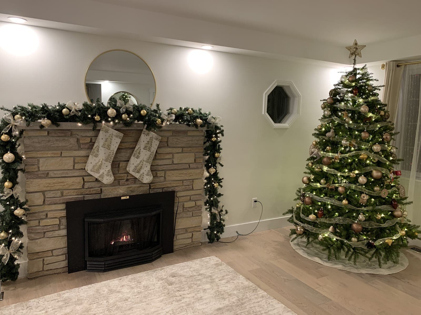 Cozy living room featuring a Christmas tree and a fireplace mantel wrapped in warm-white garland lights