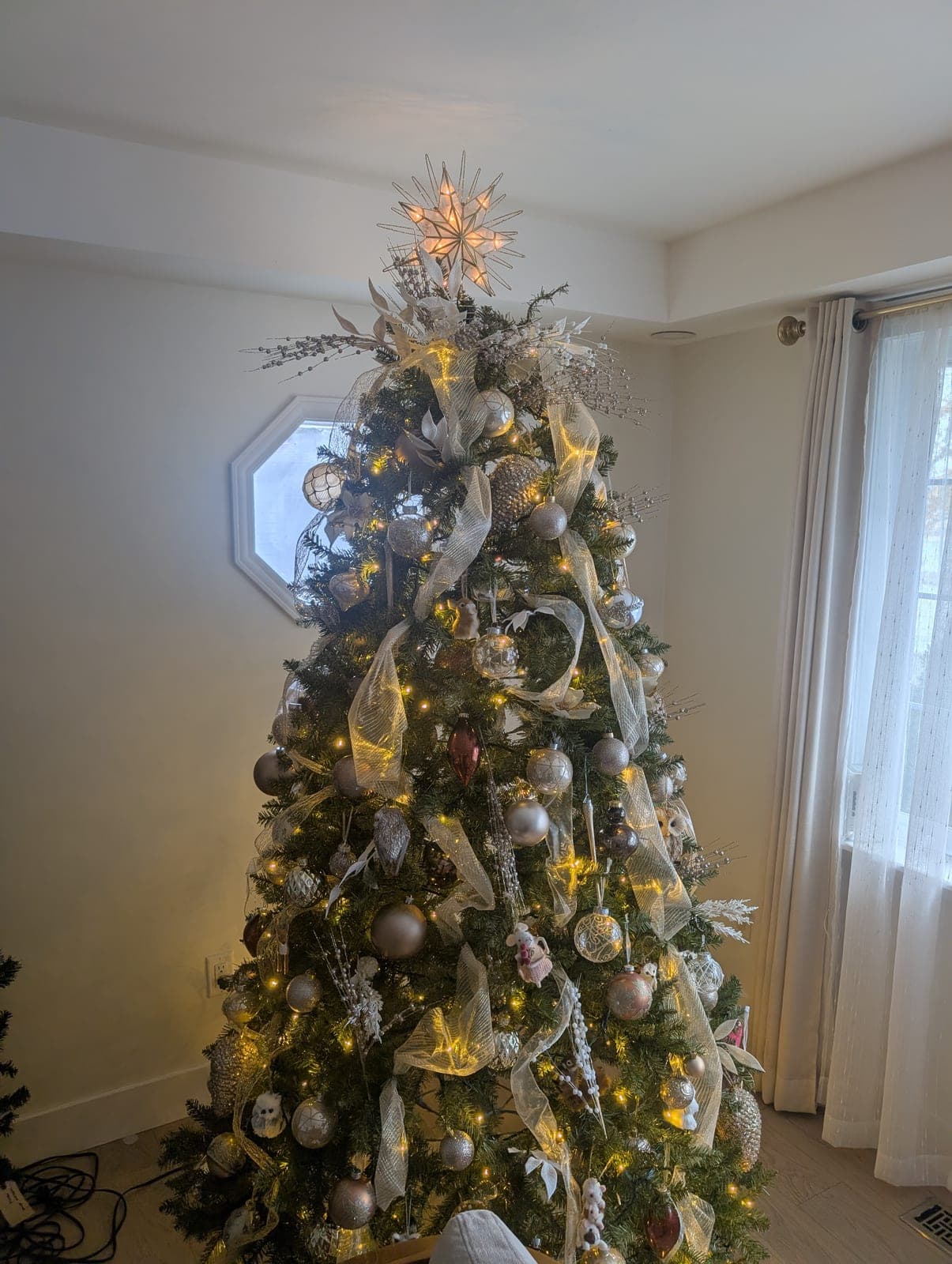 Elegantly decorated indoor Christmas tree with gold and silver ornaments and warm-white lights