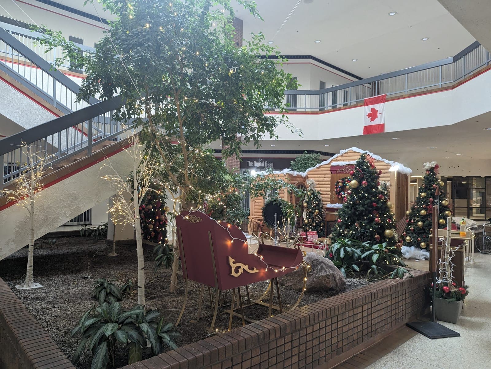 Red Christmas sleigh centrepiece lit with fairy lights in a decorated shopping mall atrium