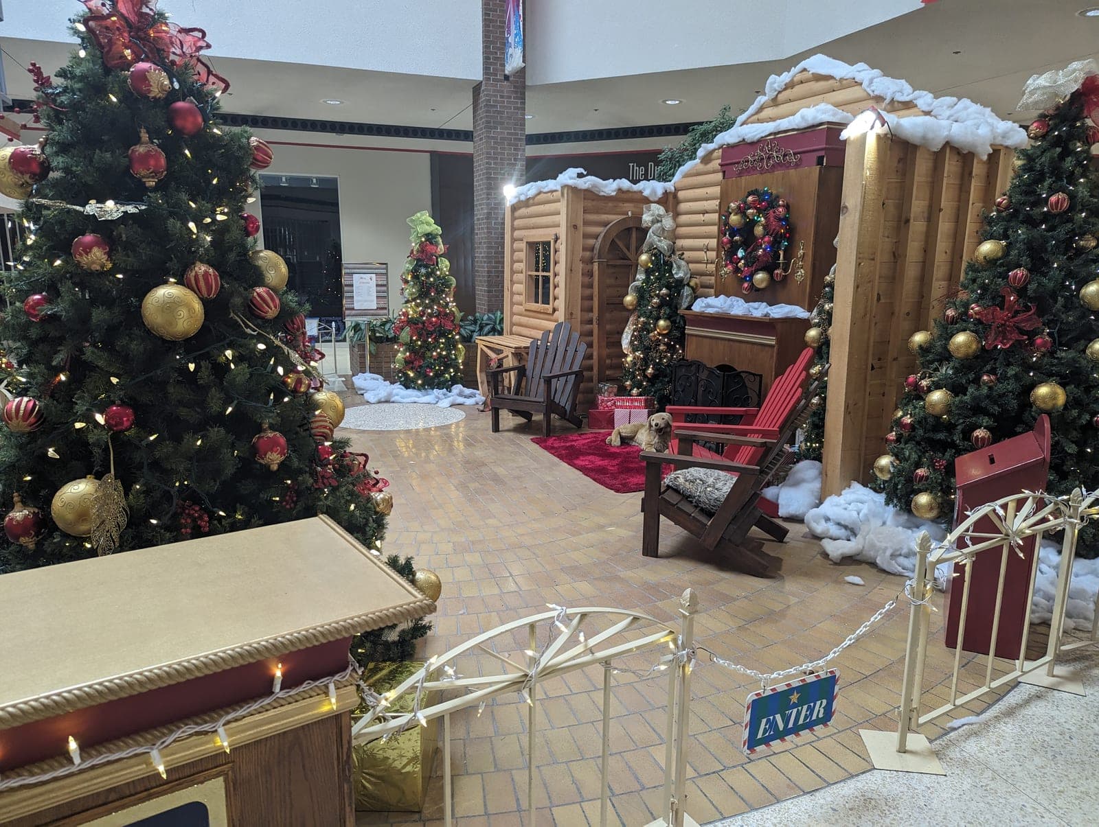 Mall Santa's cabin Christmas display with an ENTER sign, decorated trees and cozy photo set
