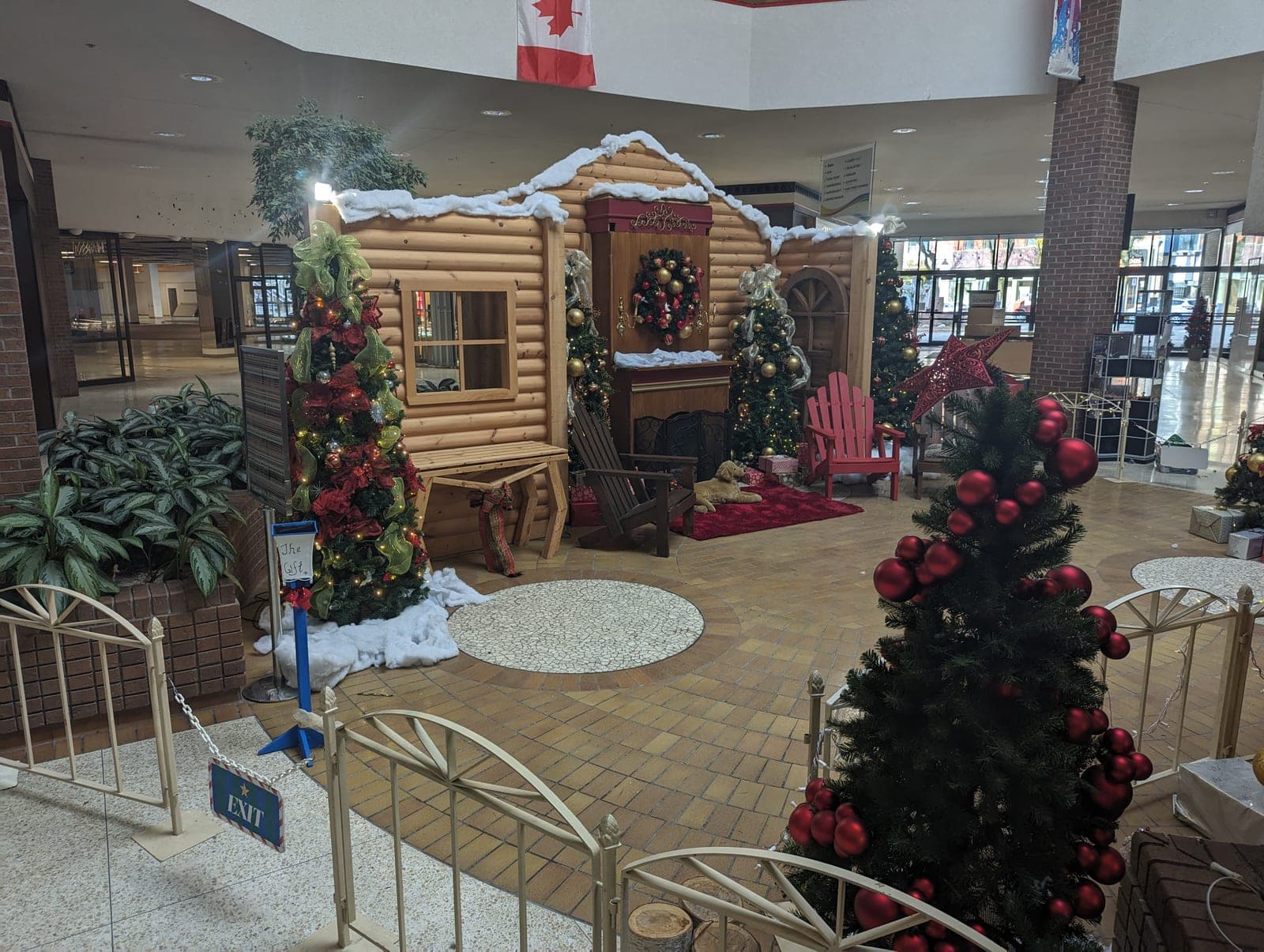 Mall Santa's cabin Christmas display with red-ornament trees and gold fencing around the photo set