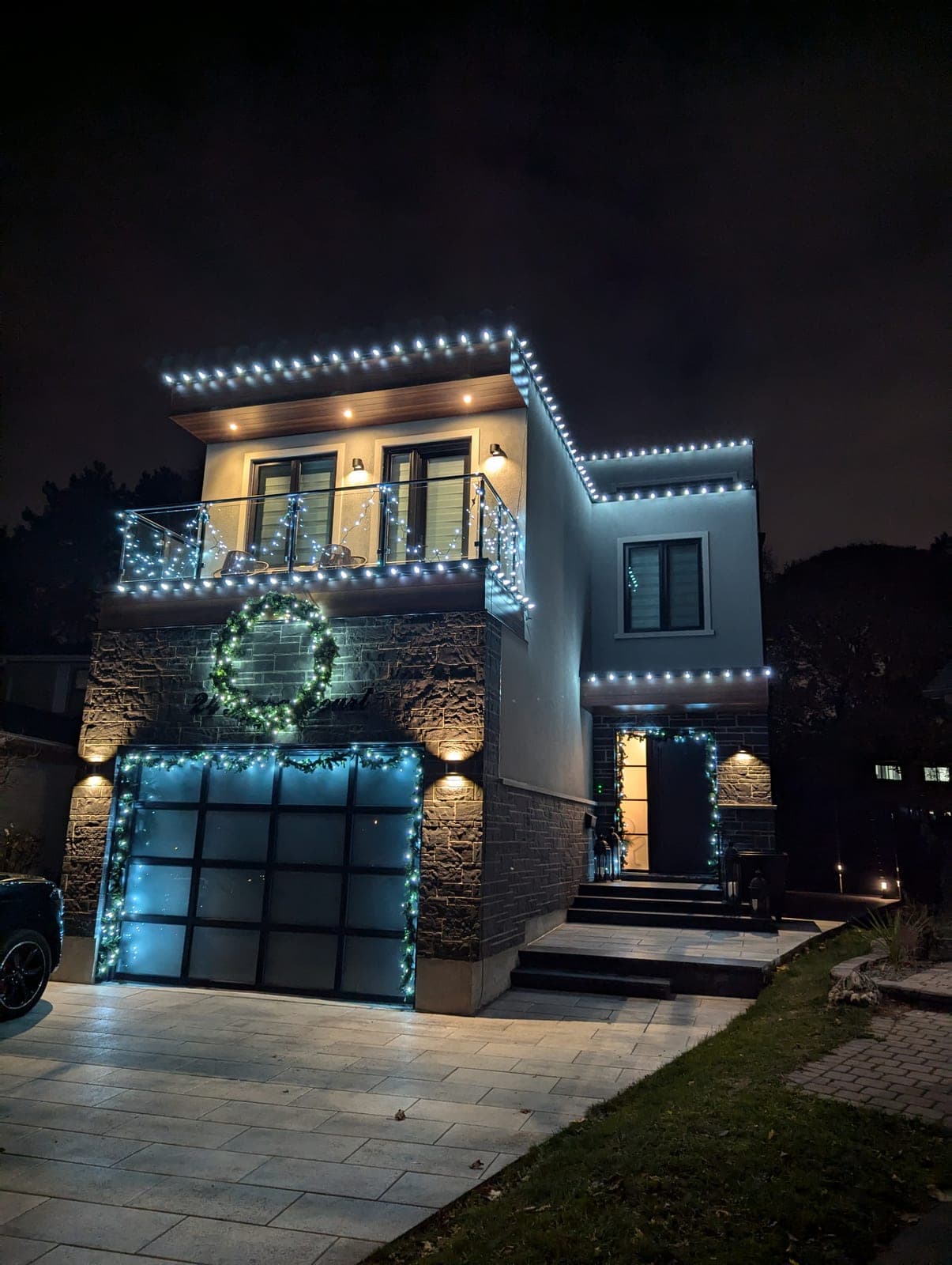 Modern home with crisp white roofline Christmas lights and illuminated garage garland at night