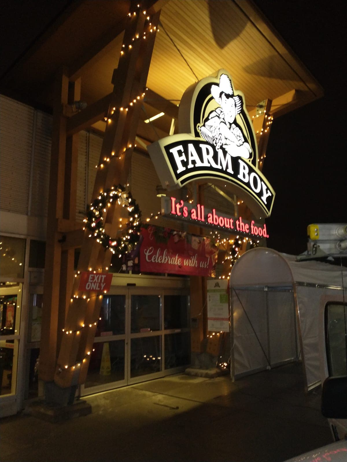 Commercial storefront post wrapped in warm-white Christmas lights with a lit wreath and garland