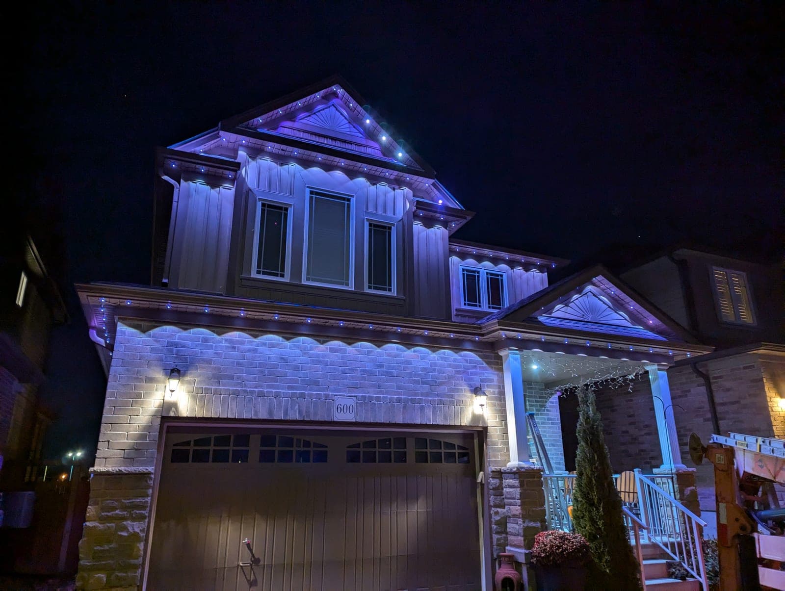 Two-storey home with blue and white icicle-style permanent LED lights outlining the eaves